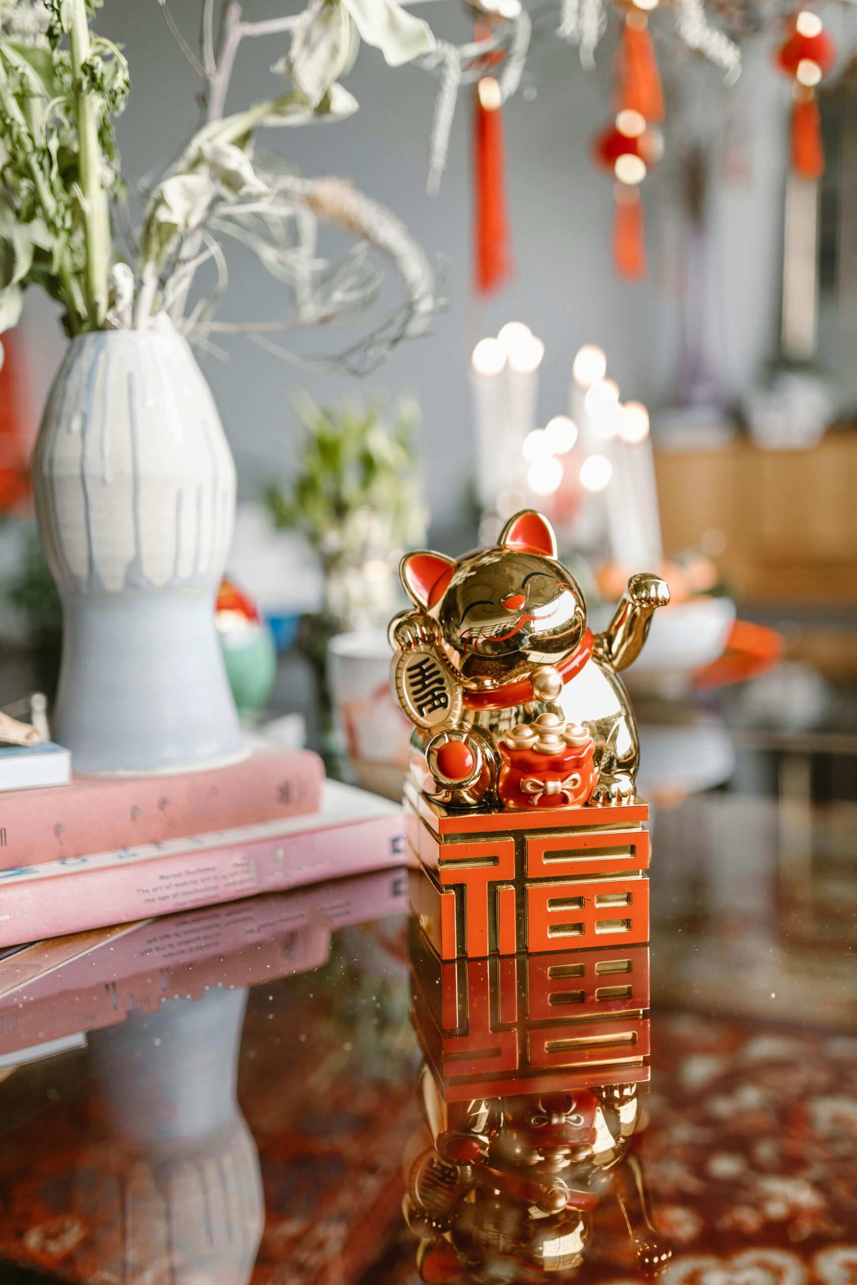 Golden Maneki Neko figurine on table with festive decor and plants, perfect for celebrations.